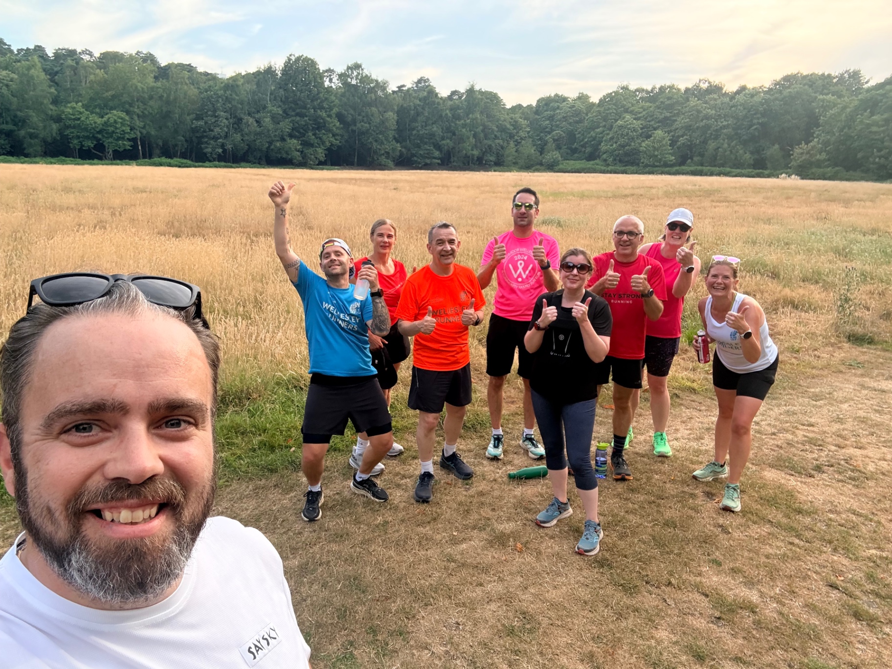 Wellesley Runners group photo in a golden field at sunset after a longer social run